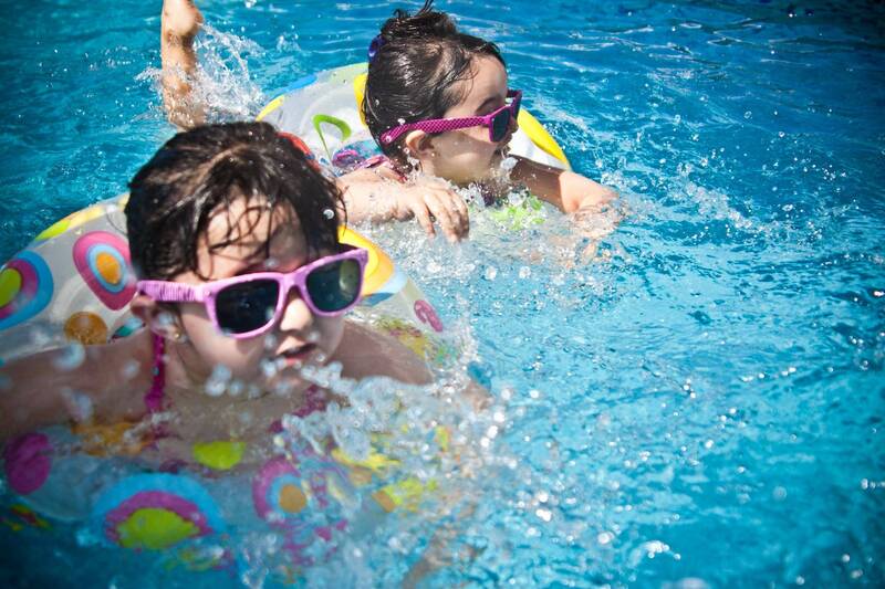 Children safely swimming in a pool with a compliant safety fence — pool safety inspection Geelong