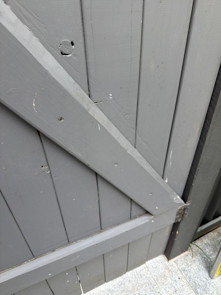 Diagonal timber brace on the outside face of a grey pool gate