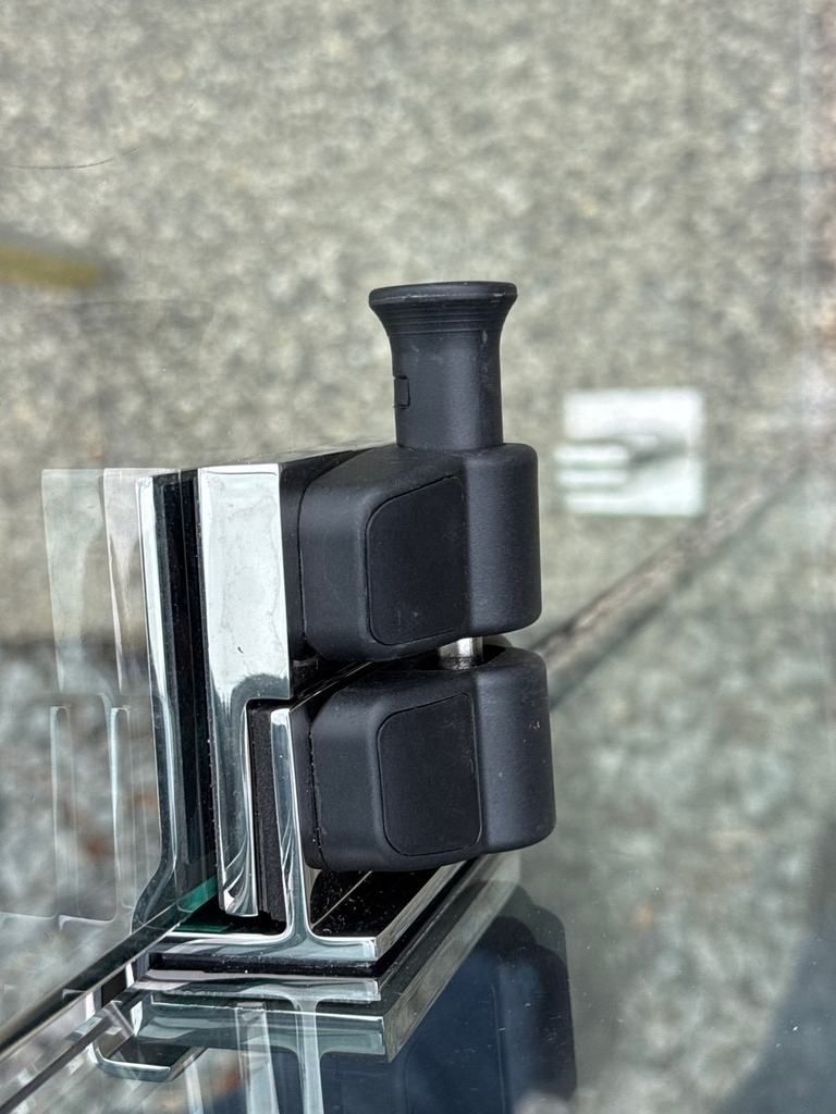 Black side-pull latch fitted to a glass pool gate panel, close up