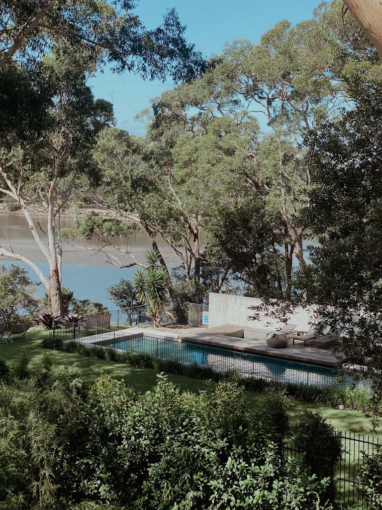 Garden and trees above a riverside property with a pool and fence in the lower yard